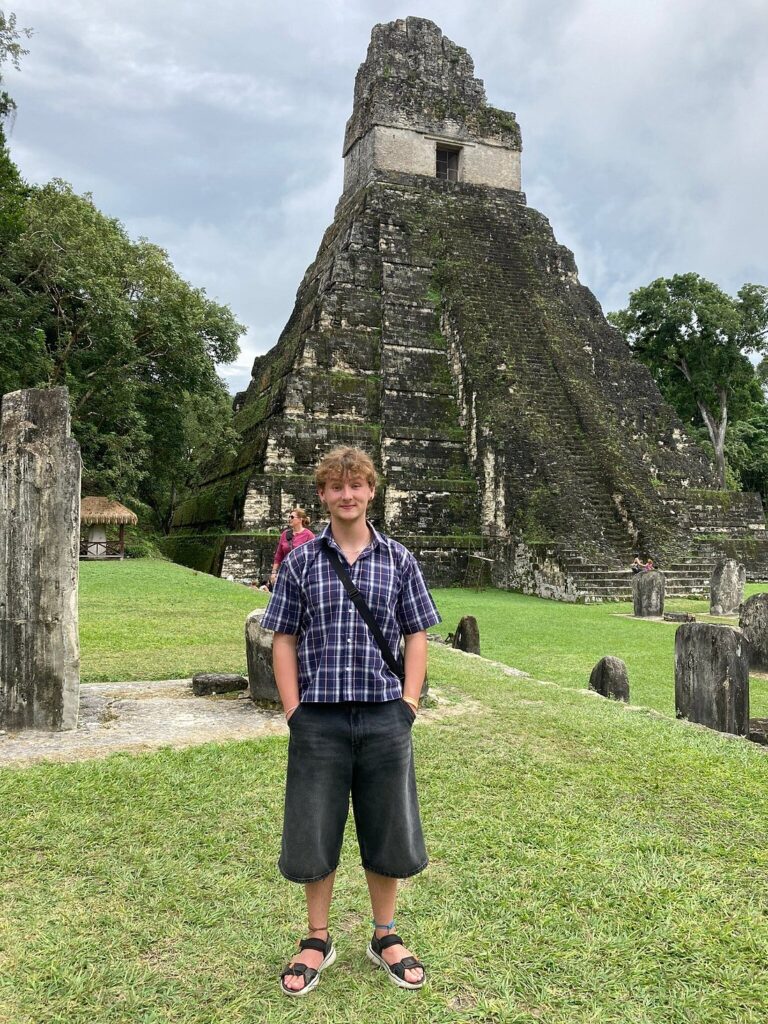 Traveler from the UK standing in front of Tikal Temple during a Pacz Tours adventure from Belize